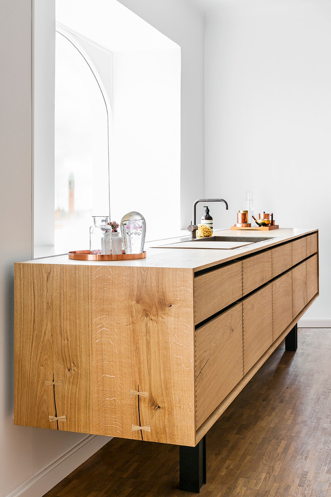 コペンハーゲンにある高級なコンテンポラリースタイルのおしゃれなキッチン (シングルシンク、フラットパネル扉のキャビネット、中間色木目調キャビネット、木材カウンター、無垢フローリング、アイランドなし、茶色い床) の写真