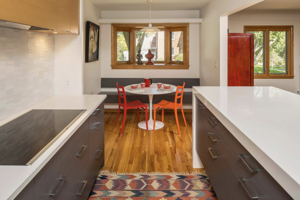Design ideas for a small contemporary galley kitchen/diner in Minneapolis with flat-panel cabinets, white cabinets, composite countertops, white splashback, ceramic splashback, white appliances, light hardwood flooring, an island, yellow floors and white worktops.