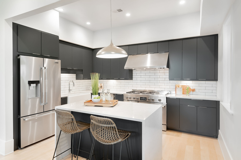 Mid-sized trendy l-shaped light wood floor and beige floor kitchen photo in Charleston with a farmhouse sink, flat-panel cabinets, gray cabinets, quartz countertops, white backsplash, subway tile backsplash, stainless steel appliances, an island and white countertops