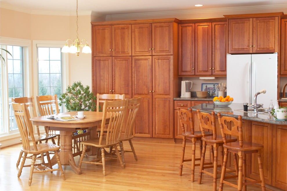 Источник вдохновения для домашнего уюта: большая прямая кухня в классическом стиле с обеденным столом, фасадами с выступающей филенкой, фасадами цвета дерева среднего тона, белой техникой, светлым паркетным полом и островом