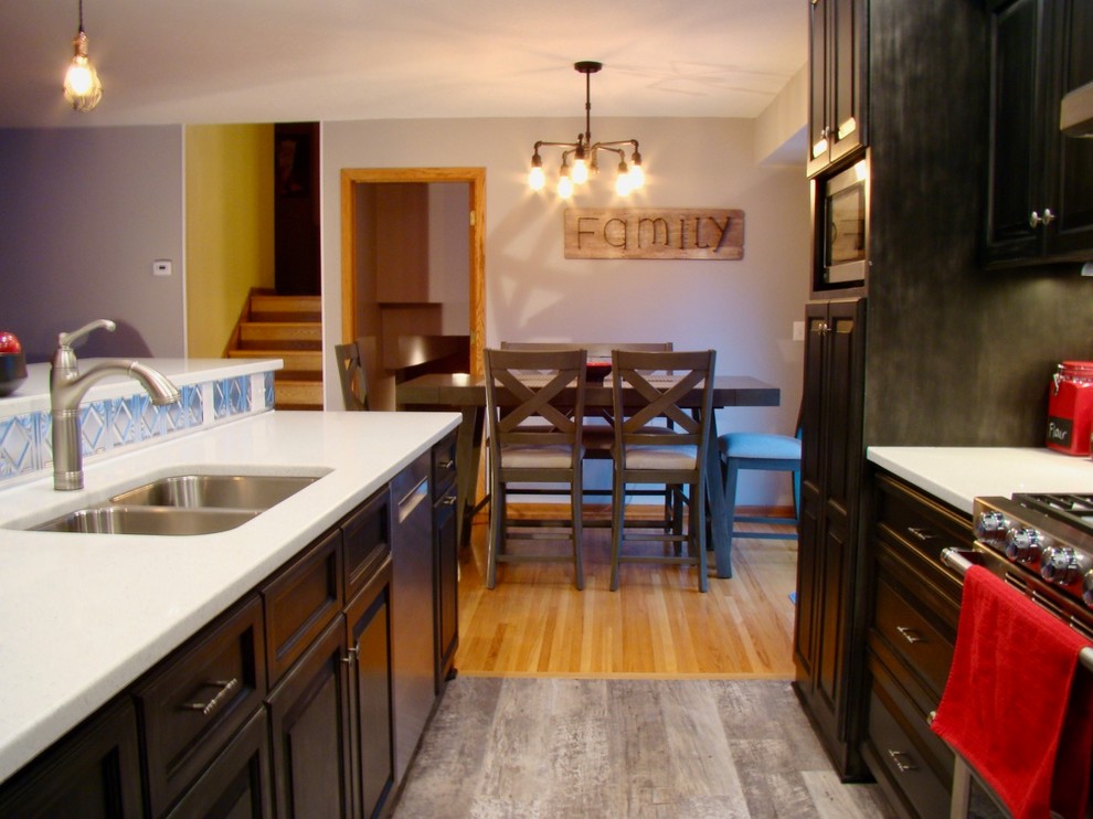 Example of an eclectic galley vinyl floor and gray floor open concept kitchen design in Minneapolis with an undermount sink, raised-panel cabinets, dark wood cabinets, quartzite countertops, metallic backsplash, metal backsplash, stainless steel appliances and a peninsula