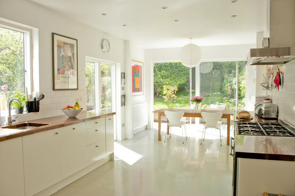 Foto di una cucina abitabile design con paraspruzzi con piastrelle diamantate, lavello sottopiano, ante lisce, ante bianche, top in legno, paraspruzzi bianco e pavimento bianco