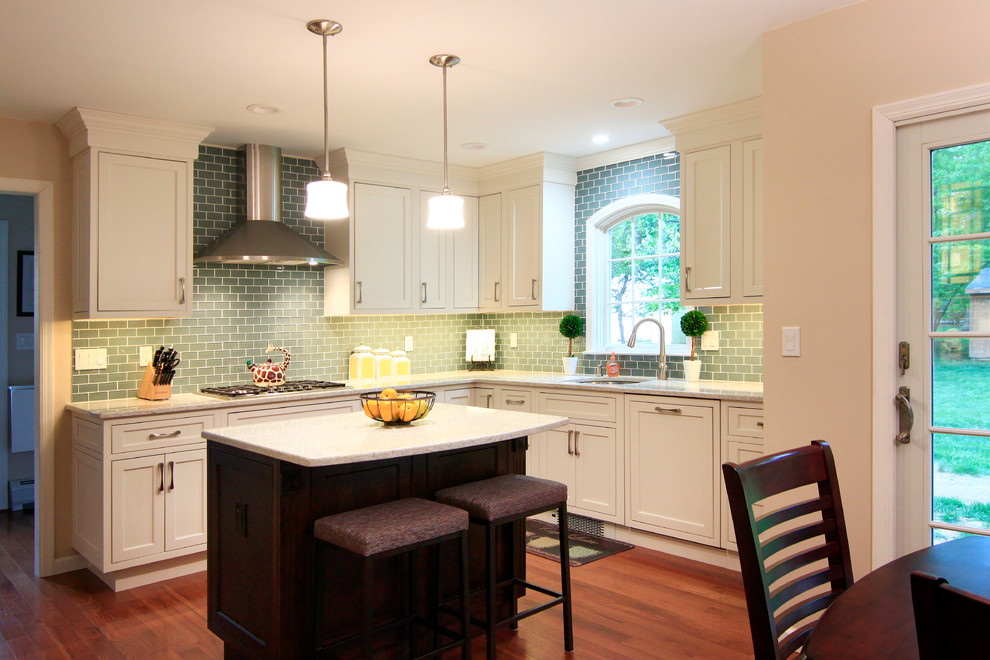 Inredning av ett klassiskt litet vit vitt kök, med en nedsänkt diskho, luckor med profilerade fronter, vita skåp, grönt stänkskydd, stänkskydd i keramik, mellanmörkt trägolv, en köksö och brunt golv
