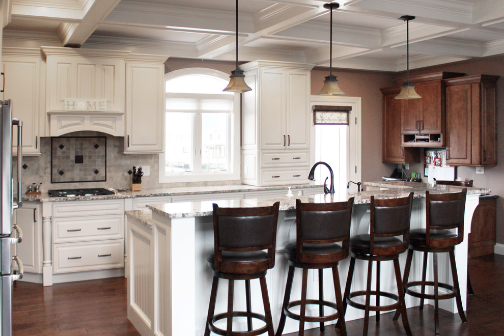 Idéer för ett mellanstort klassiskt flerfärgad kök, med en nedsänkt diskho, luckor med upphöjd panel, vita skåp, granitbänkskiva, beige stänkskydd, stänkskydd i travertin, rostfria vitvaror, mörkt trägolv, en köksö och brunt golv