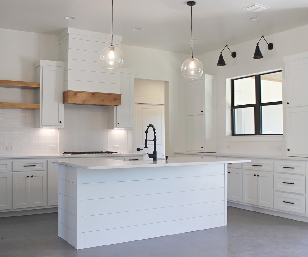 Exempel på ett lantligt vit vitt u-kök, med en rustik diskho, skåp i shakerstil, vita skåp, bänkskiva i kvartsit, vitt stänkskydd, stänkskydd i tunnelbanekakel, rostfria vitvaror, betonggolv, en köksö och grått golv