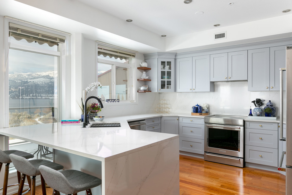Exempel på ett stort modernt kök, med en undermonterad diskho, skåp i shakerstil, grå skåp, marmorbänkskiva, rostfria vitvaror, mellanmörkt trägolv, en halv köksö, brunt golv och vitt stänkskydd