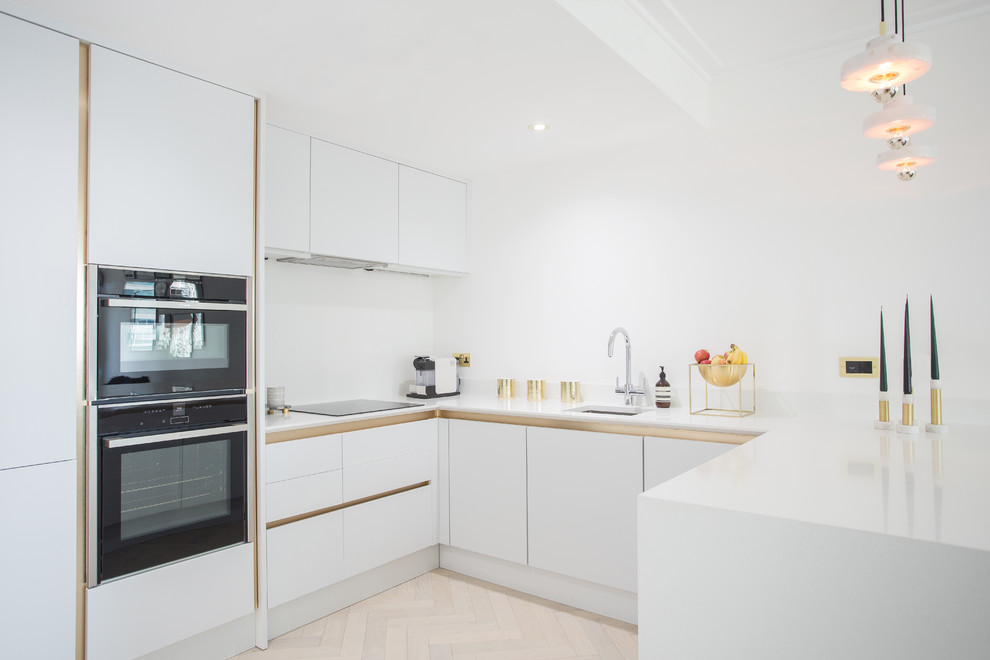 Photo of a contemporary kitchen in Other with flat-panel cabinets, white cabinets, white splashback, black appliances, light hardwood flooring and beige floors.
