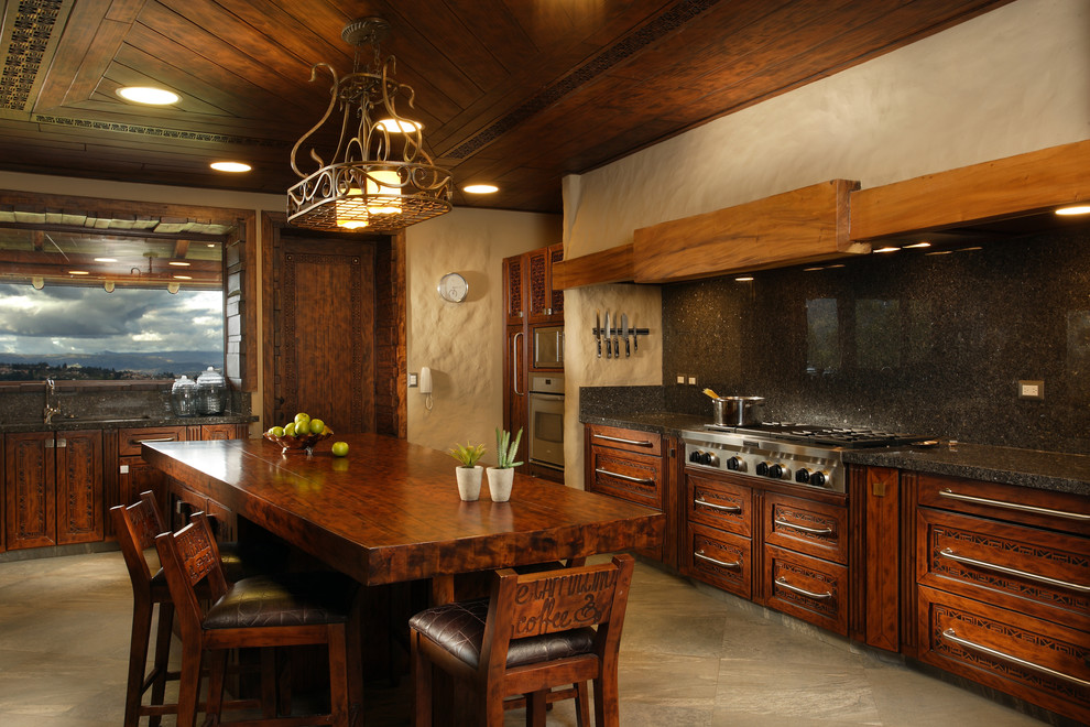 Diseño de cocina bohemia con armarios con paneles empotrados, puertas de armario de madera en tonos medios, salpicadero negro y electrodomésticos de acero inoxidable
