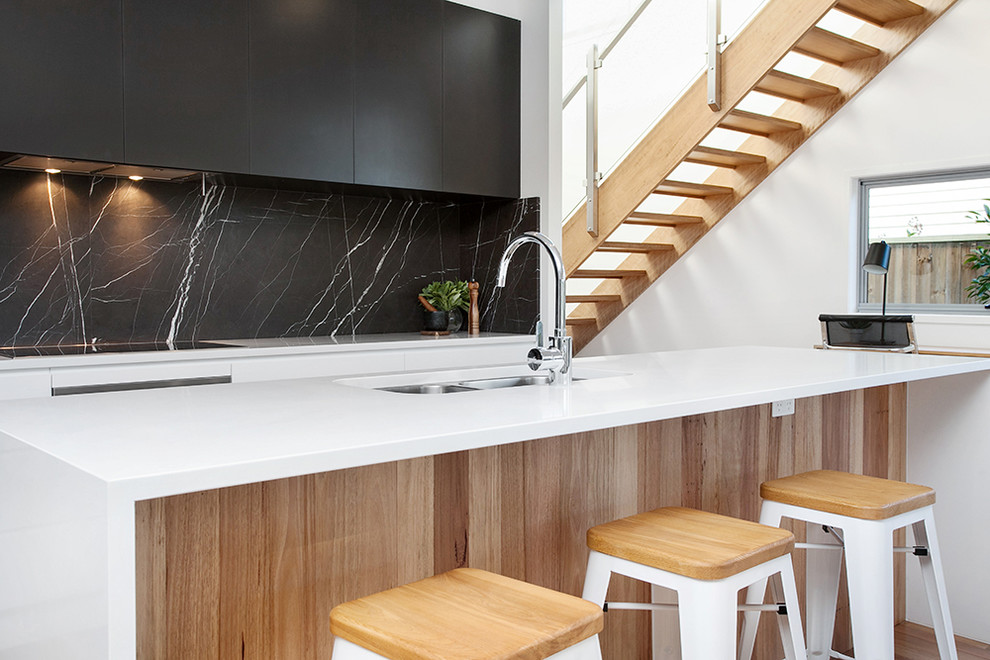 Exempel på ett nordiskt kök, med en undermonterad diskho, svarta skåp, marmorbänkskiva, svart stänkskydd, stänkskydd i marmor, rostfria vitvaror, mellanmörkt trägolv och en köksö