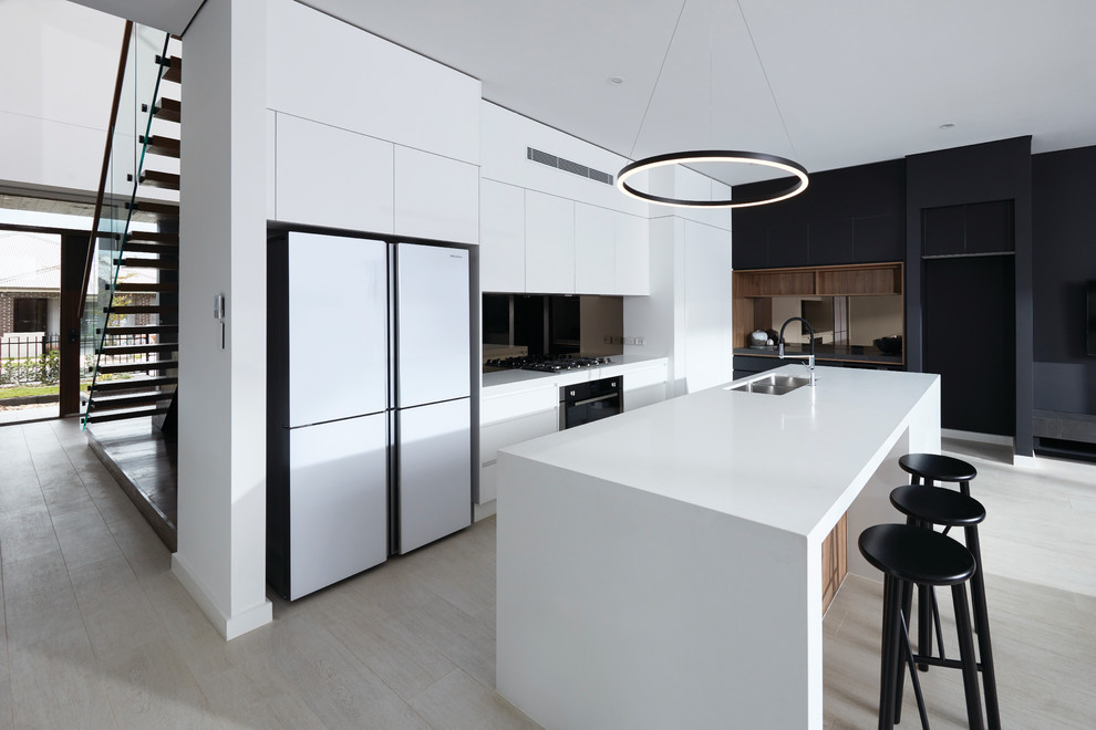 Immagine di una cucina minimalista con lavello sottopiano, ante lisce, paraspruzzi a effetto metallico, paraspruzzi a specchio, elettrodomestici bianchi, parquet chiaro, pavimento beige e top bianco
