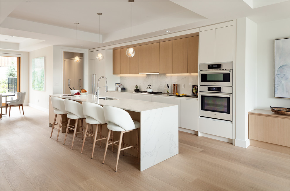 Inspiration for a contemporary galley light wood floor and beige floor eat-in kitchen remodel in Vancouver with an undermount sink, flat-panel cabinets, white cabinets, white backsplash, stone slab backsplash, paneled appliances, an island and white countertops