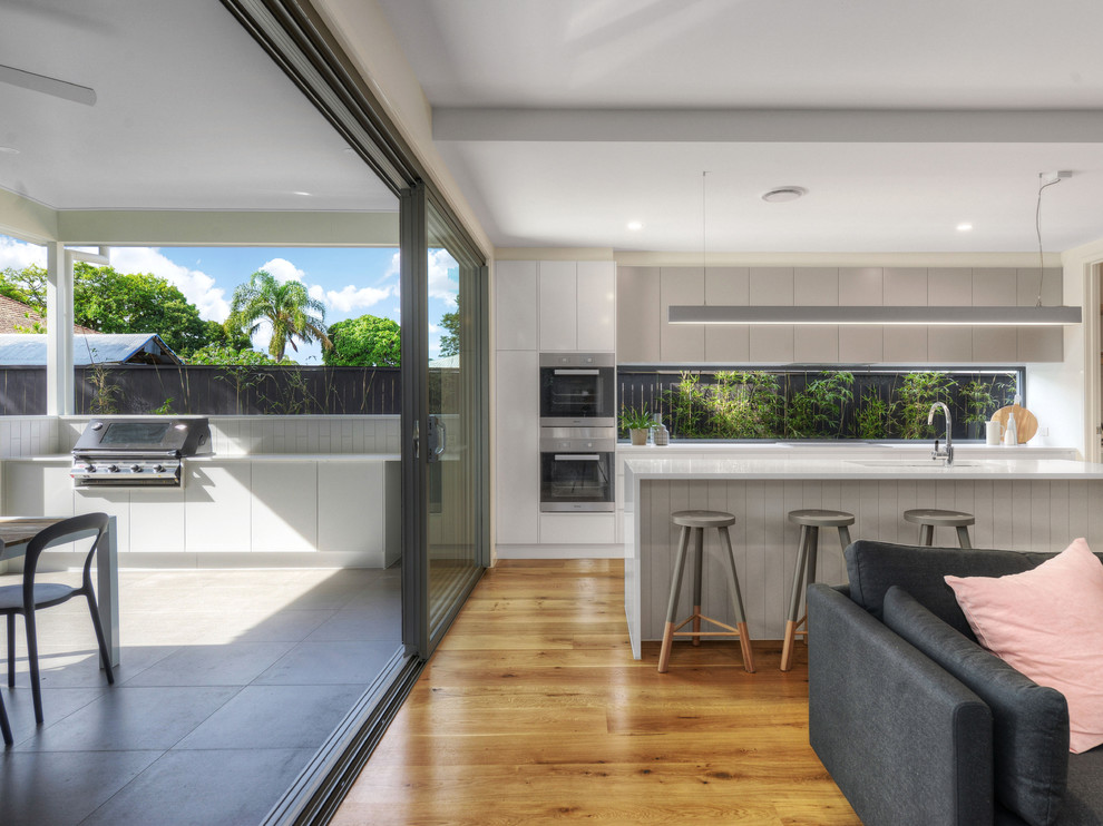 Inspiration for a classic galley open plan kitchen in Brisbane with a submerged sink, white cabinets, marble worktops, window splashback, stainless steel appliances, medium hardwood flooring and an island.