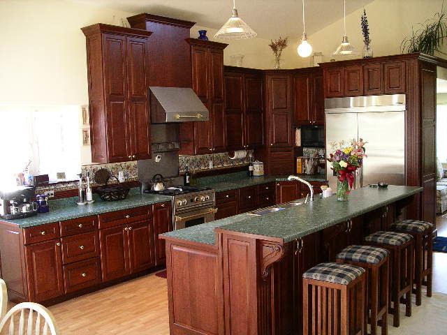 Klassisk inredning av ett kök med öppen planlösning, med en dubbel diskho, luckor med upphöjd panel, skåp i mörkt trä, bänkskiva i betong, rostfria vitvaror, ljust trägolv och en köksö