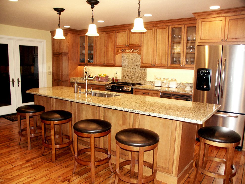 Exempel på ett klassiskt kök, med en enkel diskho, släta luckor, skåp i ljust trä, granitbänkskiva, grått stänkskydd, rostfria vitvaror, mellanmörkt trägolv och en köksö