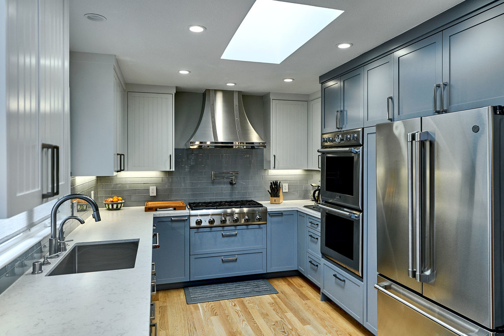 Foto på ett mellanstort vintage vit kök, med en undermonterad diskho, luckor med lamellpanel, blå skåp, marmorbänkskiva, grått stänkskydd, stänkskydd i glaskakel, rostfria vitvaror, mellanmörkt trägolv och brunt golv