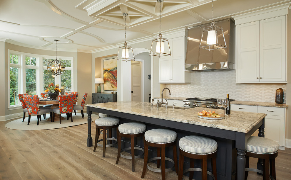 Photo of a nautical kitchen/diner in Grand Rapids with recessed-panel cabinets, beige cabinets, beige splashback, stainless steel appliances, light hardwood flooring, an island and quartz worktops.