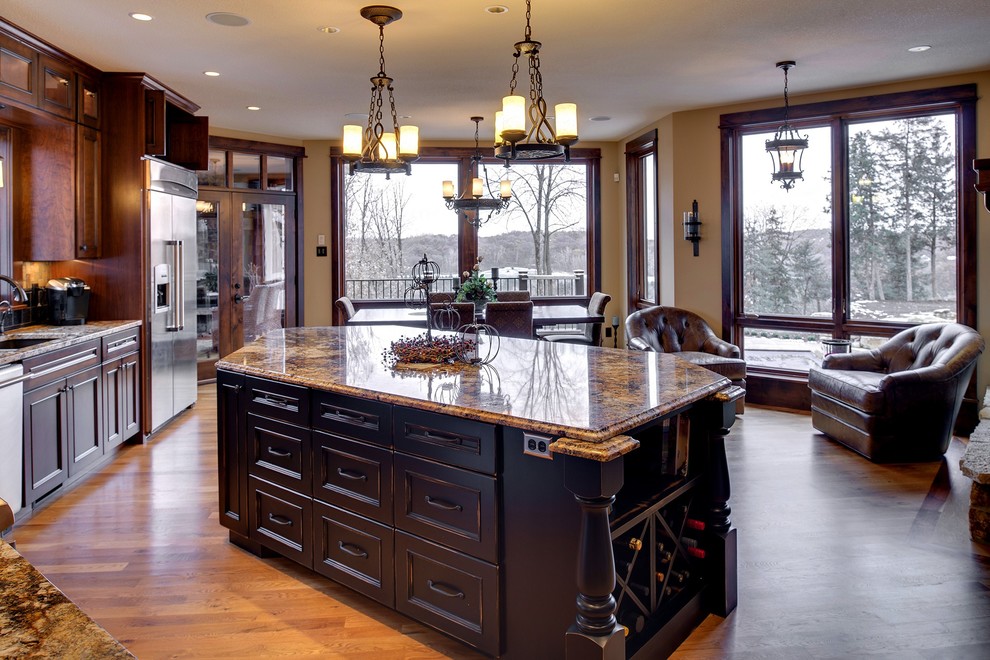 Classic kitchen in Minneapolis with a submerged sink, recessed-panel cabinets, dark wood cabinets, granite worktops, stainless steel appliances, medium hardwood flooring, an island and brown floors.