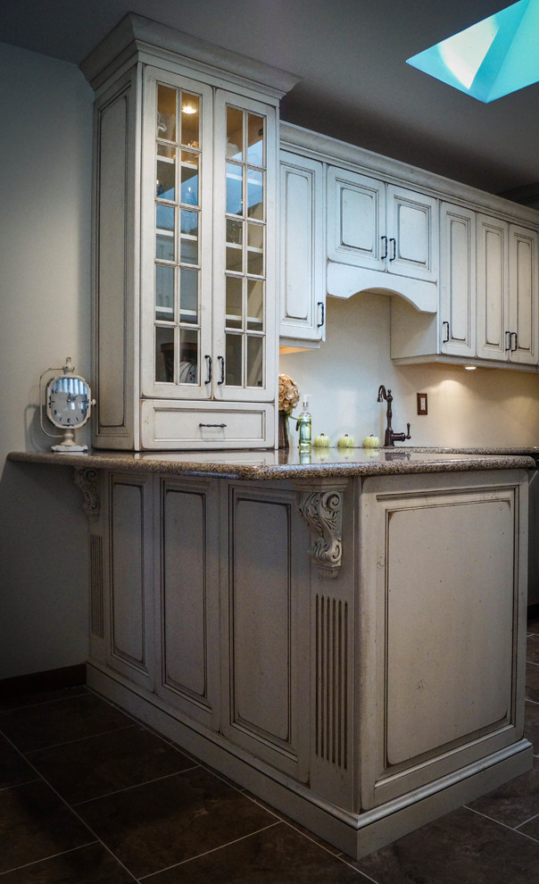 Example of a classic u-shaped eat-in kitchen design in New York with an undermount sink, raised-panel cabinets, distressed cabinets, granite countertops and stainless steel appliances