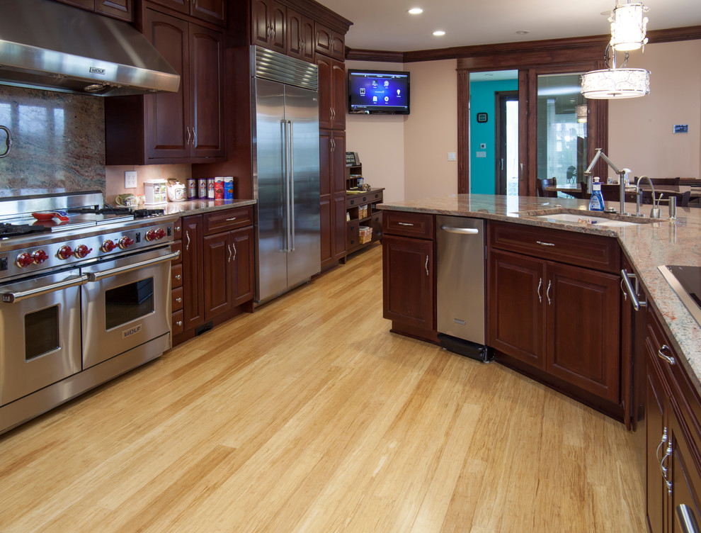 Foto di una grande cucina abitabile minimal con ante in legno bruno, top in granito, elettrodomestici in acciaio inossidabile e parquet chiaro