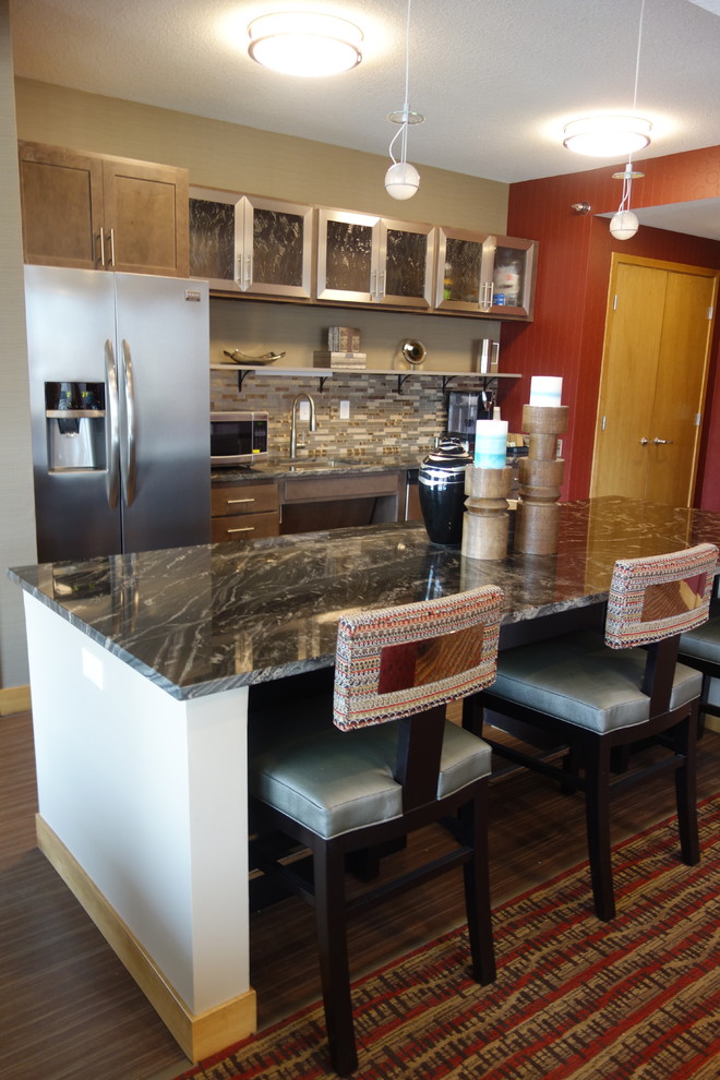 Foto på ett litet funkis linjärt kök och matrum, med en nedsänkt diskho, luckor med glaspanel, grå skåp, granitbänkskiva, flerfärgad stänkskydd, rostfria vitvaror, vinylgolv och en köksö