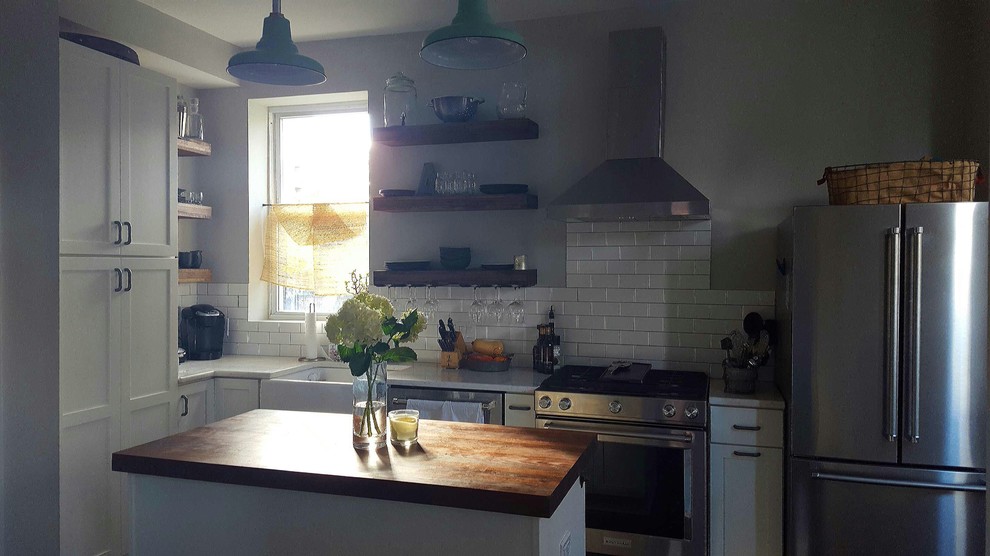 This is an example of a small shabby-chic style l-shaped kitchen/diner in DC Metro with shaker cabinets, white cabinets, wood worktops, white splashback, porcelain splashback and an island.