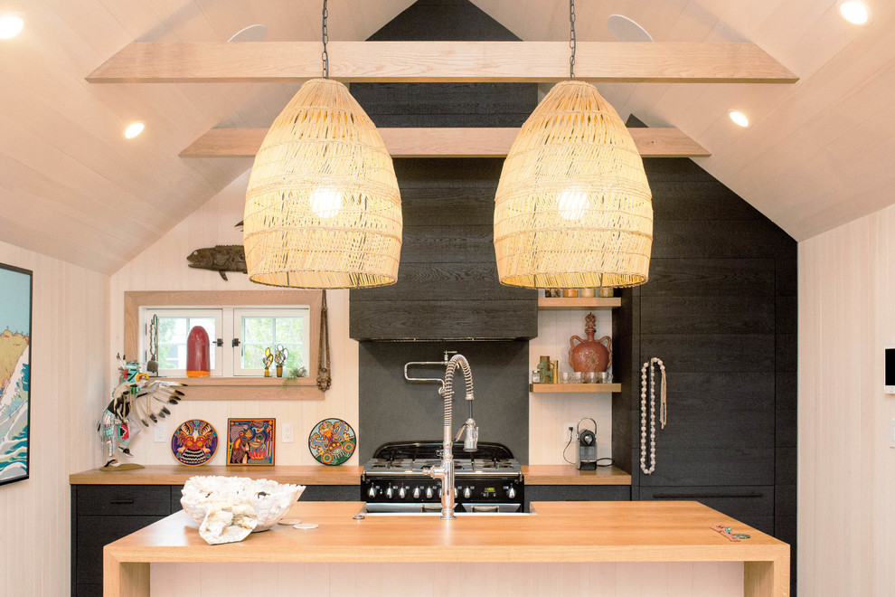 Idee per un cucina con isola centrale stile marinaro con ante lisce, ante nere, top in legno, paraspruzzi nero, elettrodomestici neri e top beige