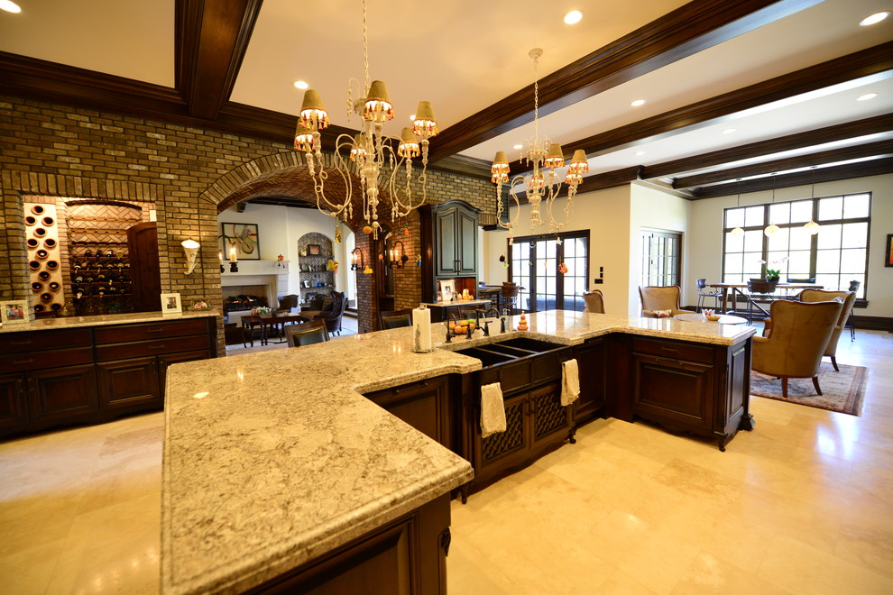 Example of a huge tuscan u-shaped travertine floor open concept kitchen design in Indianapolis with a farmhouse sink, raised-panel cabinets, dark wood cabinets, granite countertops, beige backsplash, paneled appliances, an island and stone tile backsplash
