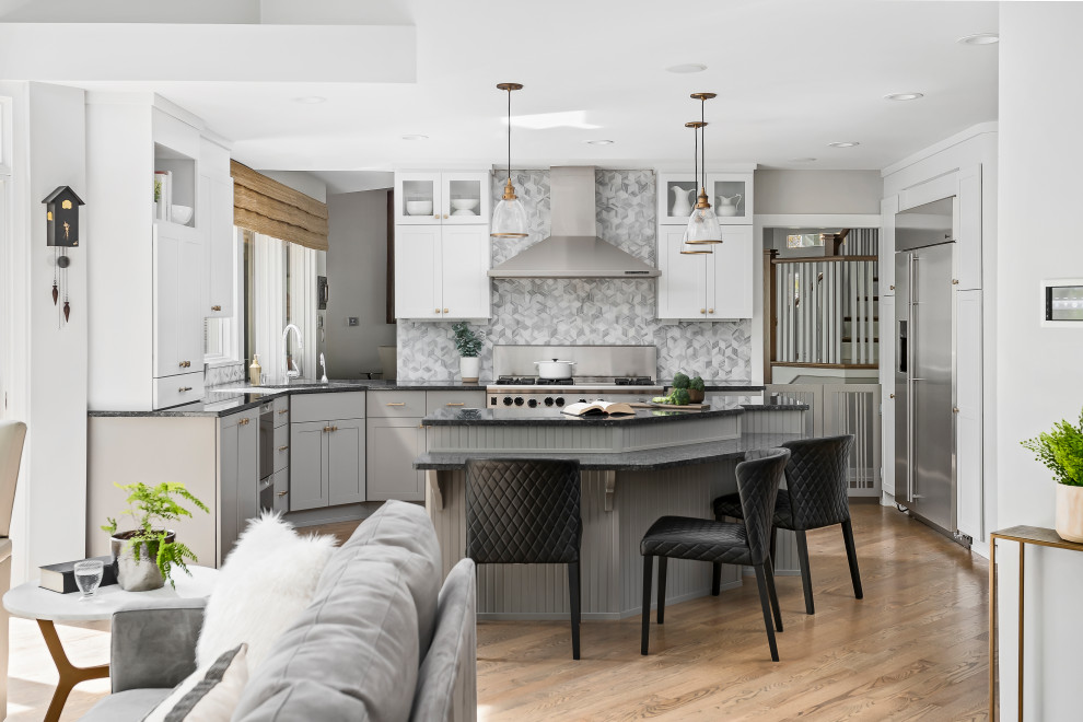 Large transitional medium tone wood floor open concept kitchen photo in Chicago with an undermount sink, shaker cabinets, white cabinets, granite countertops, gray backsplash, marble backsplash, stainless steel appliances, an island and black countertops