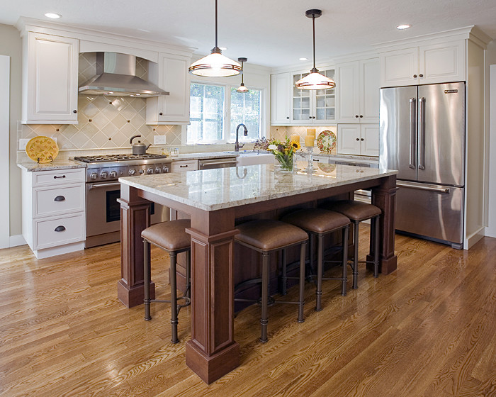 Example of a large classic l-shaped dark wood floor eat-in kitchen design in Boston with a farmhouse sink, shaker cabinets, white cabinets, marble countertops, white backsplash, ceramic backsplash, stainless steel appliances and an island