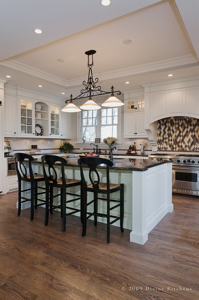 Large elegant l-shaped light wood floor eat-in kitchen photo in Boston with an undermount sink, beaded inset cabinets, white cabinets, granite countertops, multicolored backsplash, porcelain backsplash, white appliances and an island