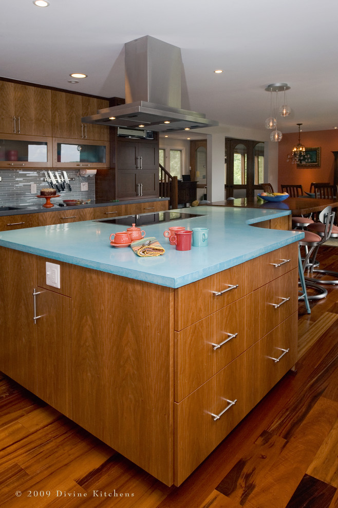 Photo of an expansive contemporary u-shaped kitchen/diner in Boston with a submerged sink, flat-panel cabinets, medium wood cabinets, concrete worktops, blue splashback, matchstick tiled splashback, stainless steel appliances, dark hardwood flooring and an island.
