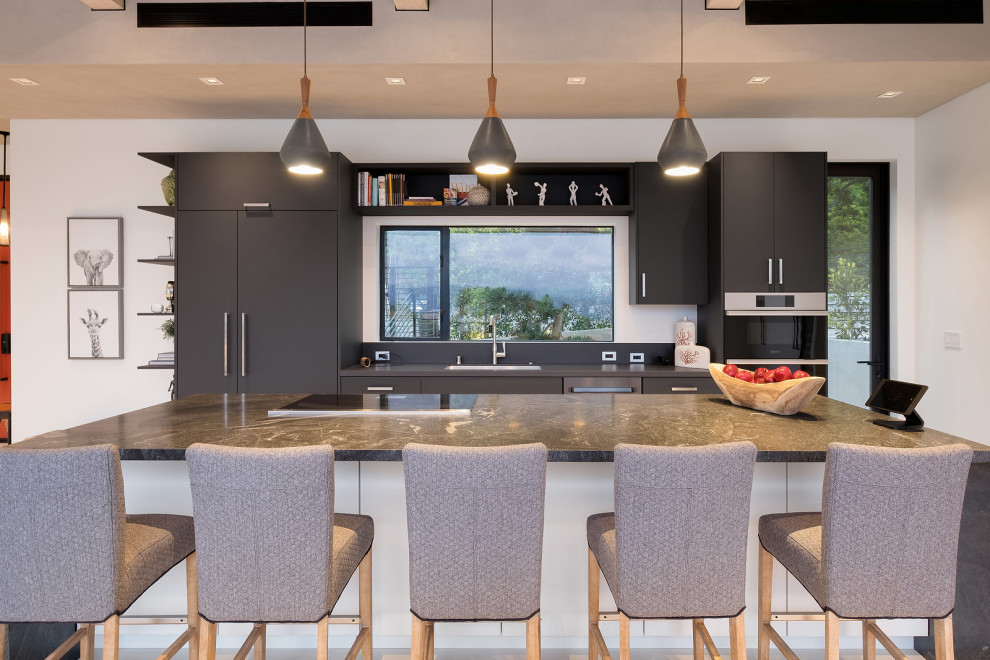 Inspiration for a contemporary galley kitchen remodel in Los Angeles with an undermount sink, flat-panel cabinets, black cabinets, an island and gray countertops