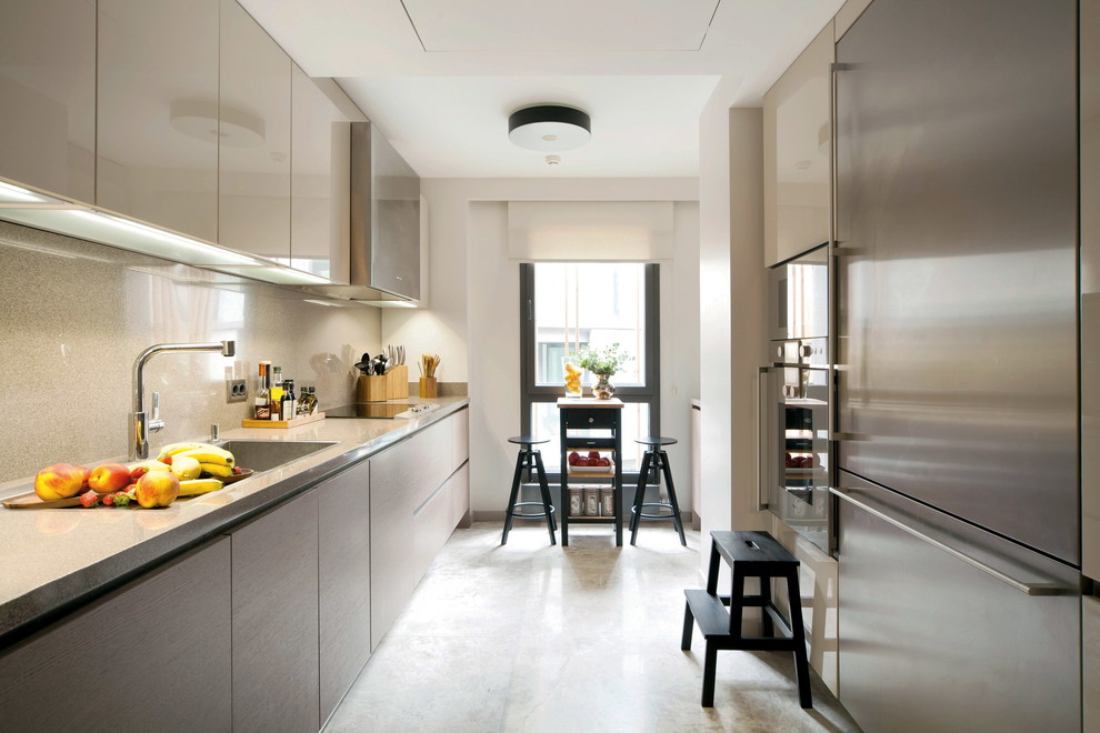 Foto de cocina rectangular contemporánea cerrada con armarios con paneles lisos, puertas de armario beige, salpicadero beige y electrodomésticos de acero inoxidable