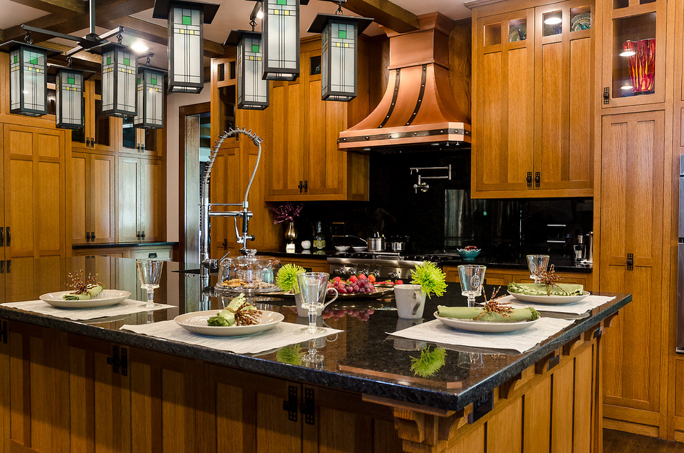 Foto di un grande cucina con isola centrale american style con ante con riquadro incassato, ante in legno scuro, top in granito, paraspruzzi nero e paraspruzzi in lastra di pietra