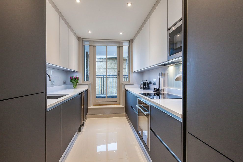 Inspiration for a small contemporary galley enclosed kitchen in London with a built-in sink, flat-panel cabinets, white cabinets, quartz worktops, white splashback, glass sheet splashback, integrated appliances, porcelain flooring and no island.