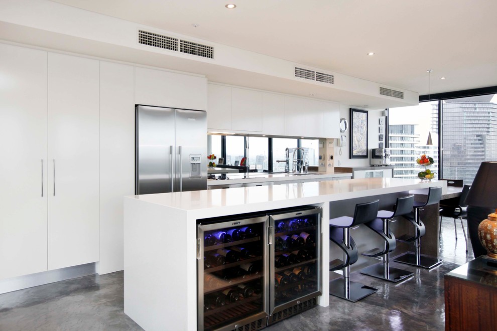 Exempel på ett stort modernt kök, med en undermonterad diskho, släta luckor, vita skåp, bänkskiva i kvarts, rostfria vitvaror, betonggolv och en köksö
