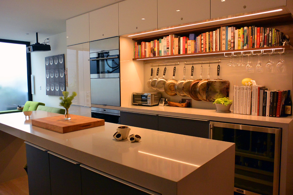 Immagine di una piccola cucina moderna con ante lisce, ante grigie, top in quarzo composito, paraspruzzi bianco, elettrodomestici in acciaio inossidabile e parquet chiaro