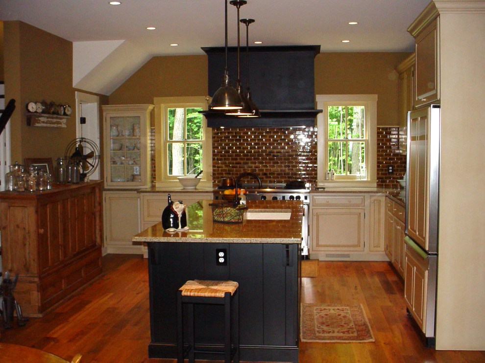 Inredning av ett klassiskt kök, med en undermonterad diskho, luckor med upphöjd panel, skåp i slitet trä, granitbänkskiva, brunt stänkskydd, stänkskydd i tunnelbanekakel och integrerade vitvaror