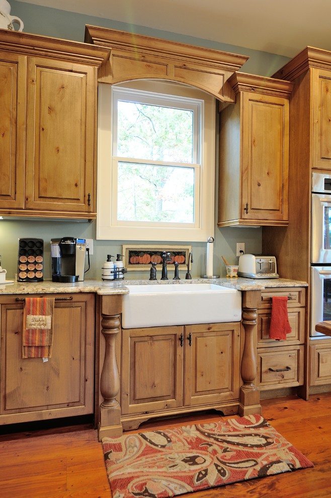 Foto på ett rustikt kök, med en rustik diskho, skåp i mellenmörkt trä, rostfria vitvaror och mellanmörkt trägolv