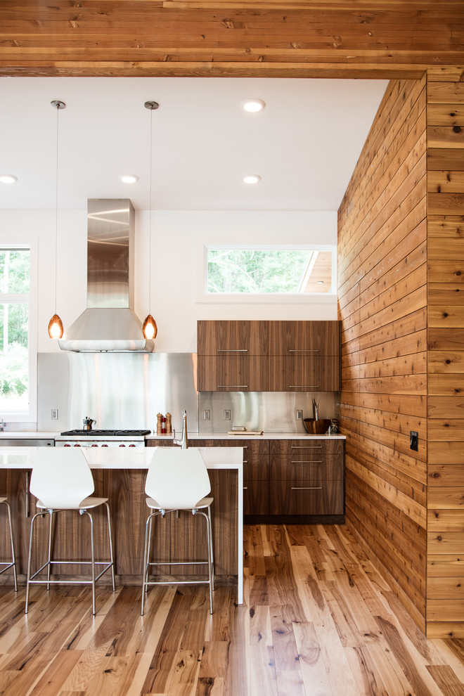 Cette photo montre une cuisine tendance en bois foncé avec un placard à porte plane, une crédence grise, un électroménager en acier inoxydable, un sol en bois brun et îlot.