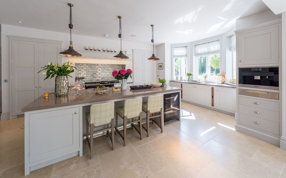 Example of a farmhouse l-shaped kitchen design in Oxfordshire with shaker cabinets, gray cabinets, blue backsplash and an island