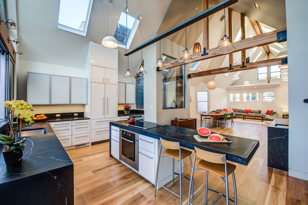 Offene Moderne Küche in L-Form mit flächenbündigen Schrankfronten, weißen Schränken, braunem Holzboden und Kücheninsel in San Francisco