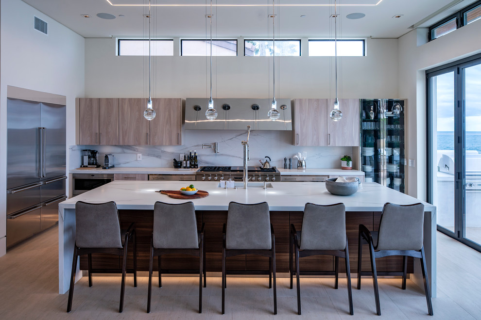 Example of a trendy l-shaped beige floor kitchen design in San Diego with an integrated sink, flat-panel cabinets, light wood cabinets, white backsplash, stainless steel appliances, an island and white countertops