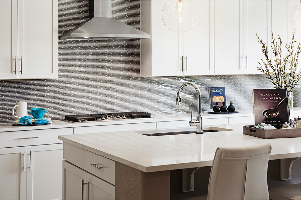 デンバーにあるコンテンポラリースタイルのおしゃれなアイランドキッチン (白いキャビネット、シルバーの調理設備、白いキッチンカウンター) の写真
