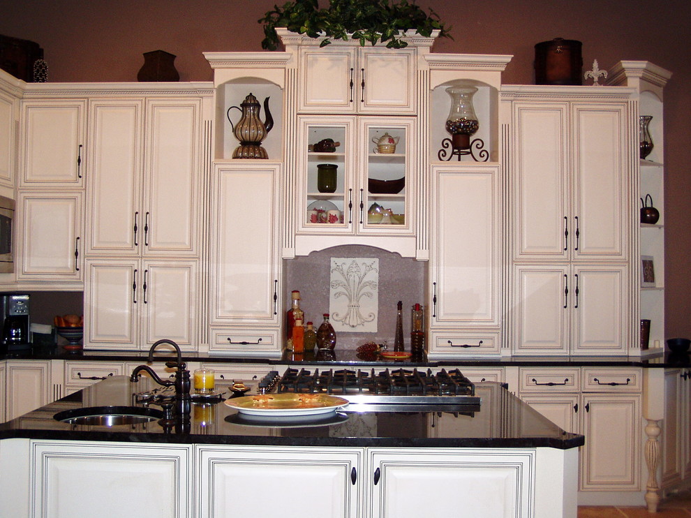 Immagine di un'ampia cucina classica con lavello sottopiano, ante con bugna sagomata, ante in legno chiaro, top in granito, elettrodomestici in acciaio inossidabile, pavimento in gres porcellanato e 2 o più isole