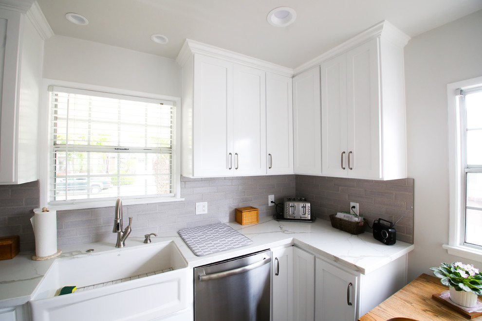 Exempel på ett mellanstort klassiskt vit vitt kök, med en undermonterad diskho, skåp i shakerstil, vita skåp, bänkskiva i kvartsit, grått stänkskydd, stänkskydd i tunnelbanekakel, rostfria vitvaror, ljust trägolv och grått golv