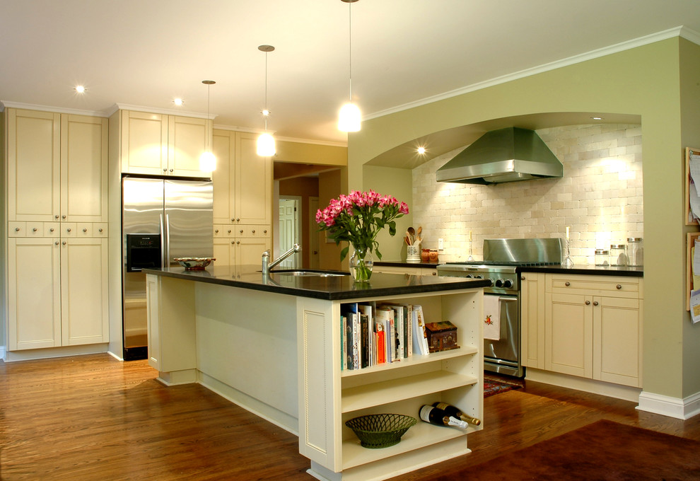 Imagen de cocina tradicional con electrodomésticos de acero inoxidable, puertas de armario beige, salpicadero beige y salpicadero de piedra caliza