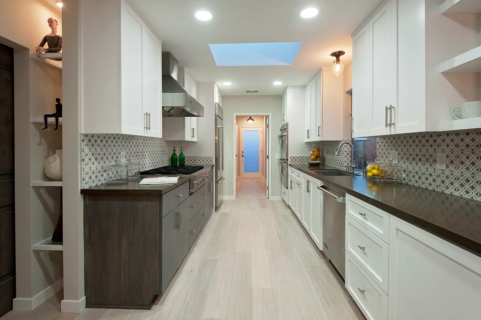 Inspiration for a classic galley enclosed kitchen in Los Angeles with a submerged sink, shaker cabinets, white cabinets, multi-coloured splashback, stainless steel appliances, light hardwood flooring and no island.