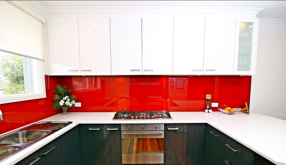 Foto di una cucina minimal di medie dimensioni con lavello a doppia vasca, ante lisce, ante bianche, top in laminato, paraspruzzi rosso, paraspruzzi con lastra di vetro, elettrodomestici in acciaio inossidabile e nessuna isola