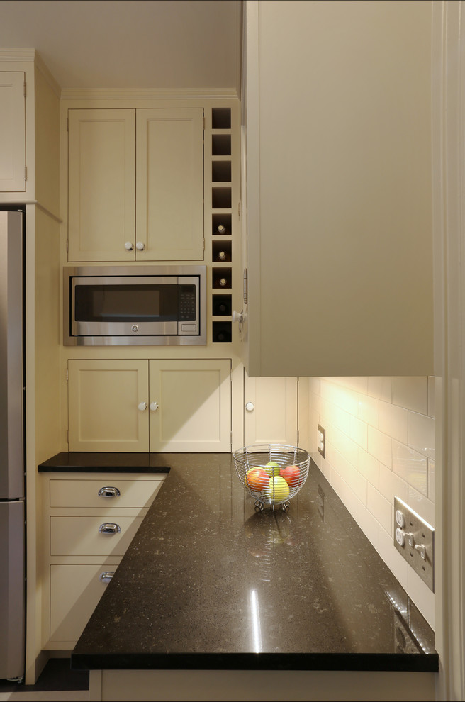 ポートランドにある高級な小さなトラディショナルスタイルのおしゃれなキッチン (アンダーカウンターシンク、落し込みパネル扉のキャビネット、白いキャビネット、クオーツストーンカウンター、白いキッチンパネル、サブウェイタイルのキッチンパネル、シルバーの調理設備、リノリウムの床、アイランドなし) の写真